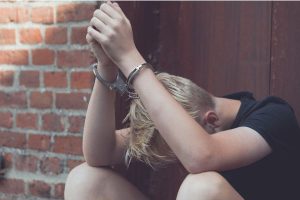 Young man in handcuffs -- pranks that cross the line have serious consequences that may need criminal defense attorney
