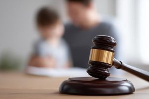 Child with parent in background with gavel in foreground; how criminal charges can impact custody agreements